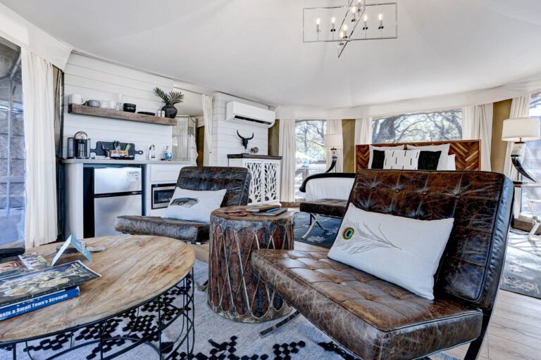 Interior of the Chisum safari tent at Spoon Mountain Glamping, leather furniture and earthy wood tones