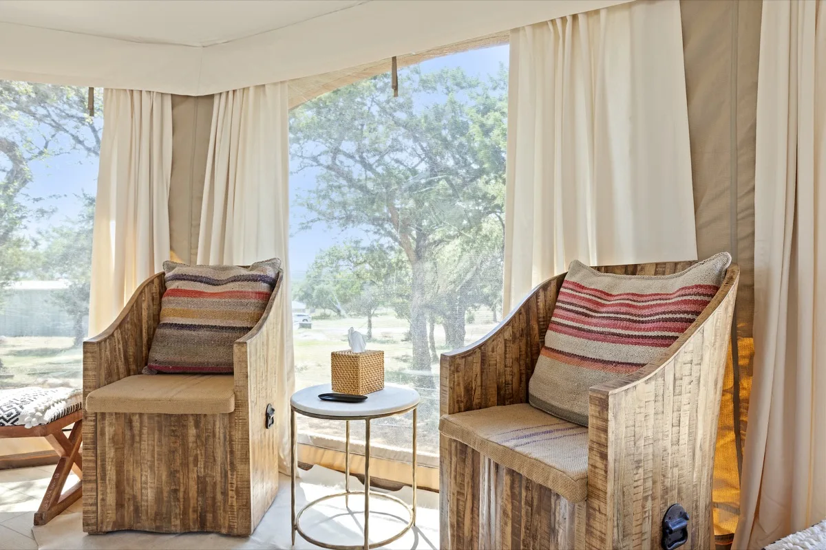 Rustic lounge chairs and side table inside the Spoon Mountain Spa Tent, Wimberley Texas